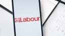 Labour Party logo on a phone screen, with office stationary in the background