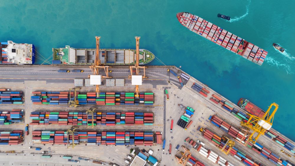 Top down view of freeport with freight ship passing by shore