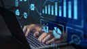 Person working on laptop, with graphs showing economic data superimposed in the foreground