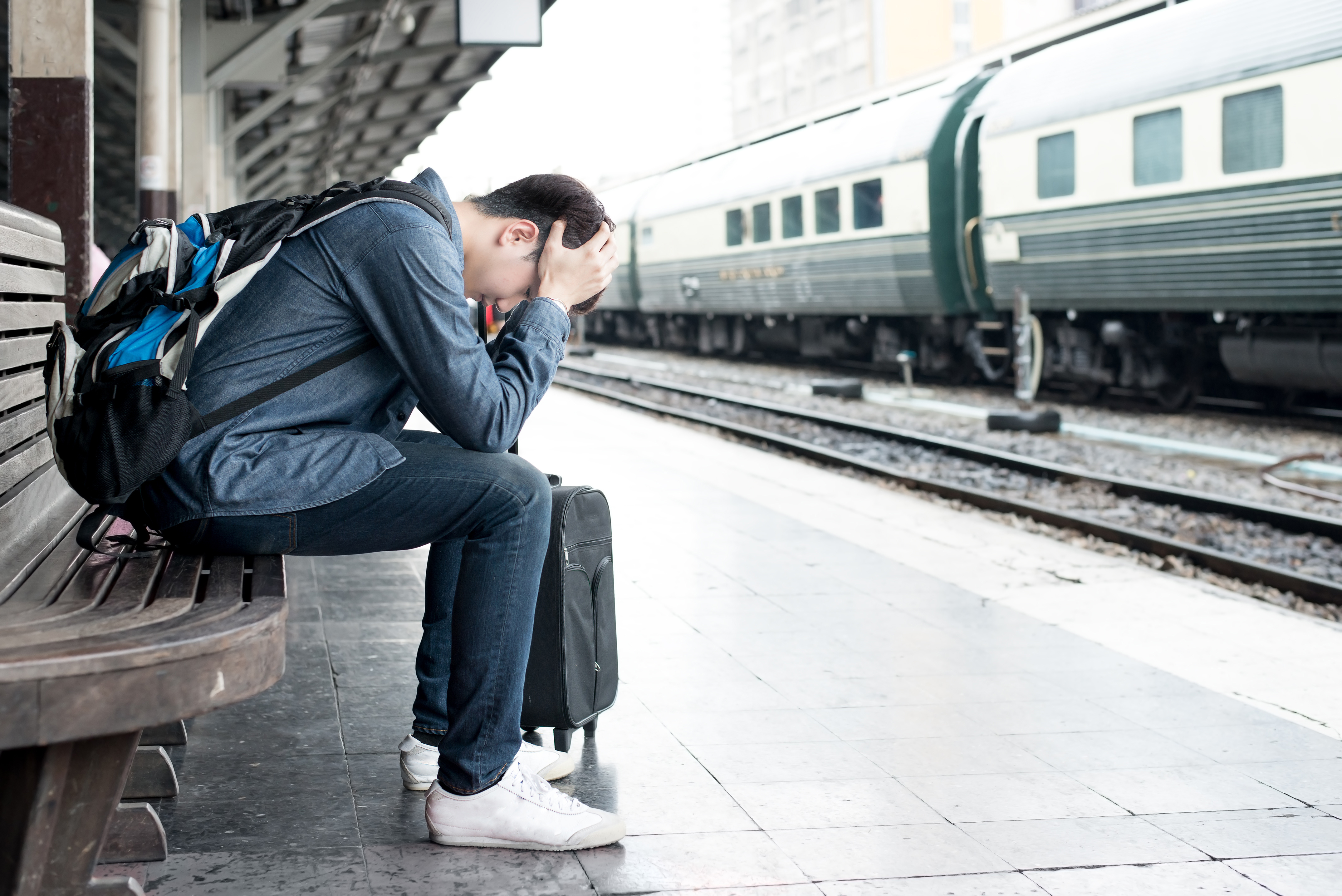 Man with head in hands at train station