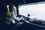 Lorry driver sitting in front of steering wheel, driving large truck along a motorway