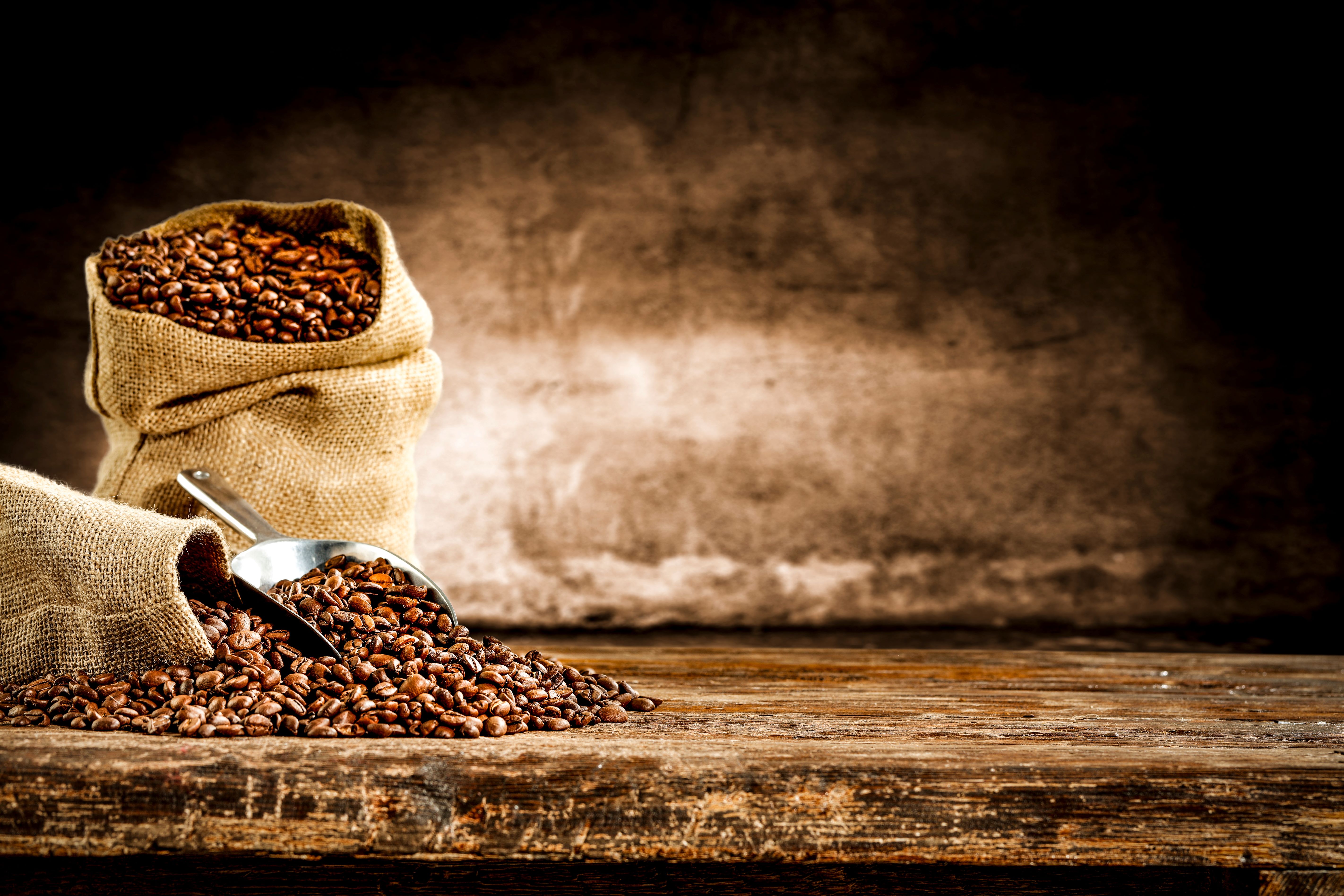 Coffee beans spilling out of a sack on a wooden table