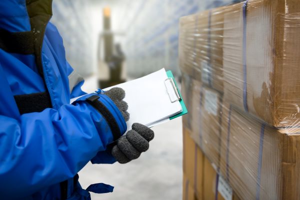 Worker in hazmat suit checking goods with a clipboard