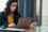 Woman sitting at a table, looking at a laptop and business records 